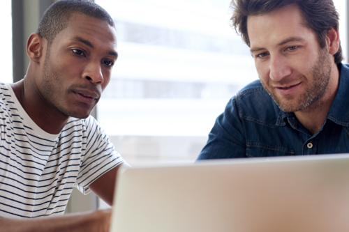Two men looking at IT services on a grey laptop
