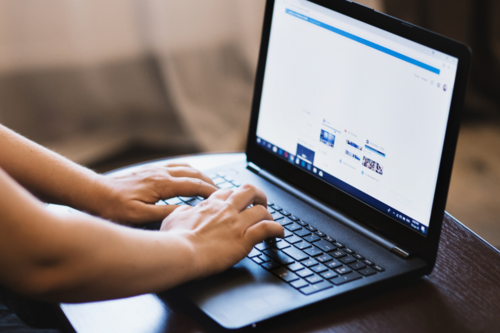 A photo of a person typing on a nice new laptop.