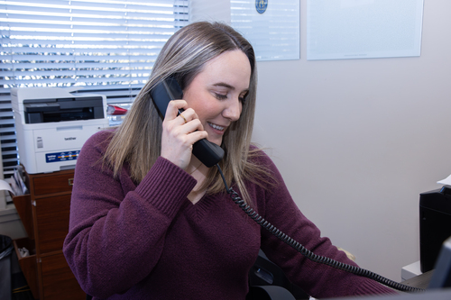 Woman at a desk answering the phone at NSG's office. 